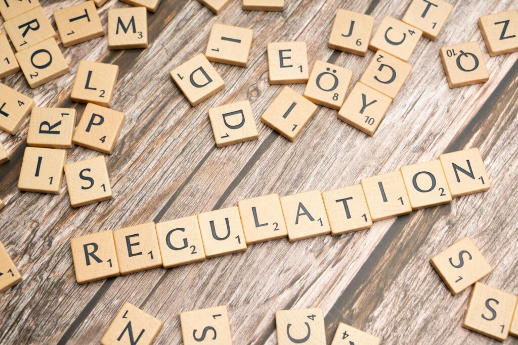 pexels photo 19813733 19813733 Wooden letter tiles spelling 'Regulation' on a textured wood background, conveying themes of compliance and structure.